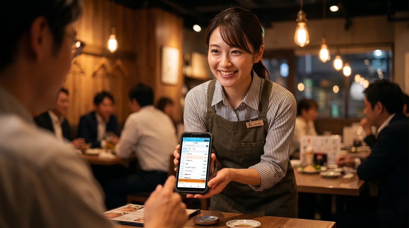 お客様にスマートフォンの注文画面を見せるホールスタッフ（AI生成の利用イメージ）